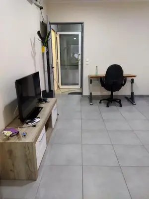 a living room with a tv and a desk and a chair at Cozy apartment near to the airport in Kouvarás