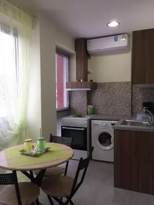 a kitchen with a table and a washing machine at Cozy apartment near to the airport in Kouvarás