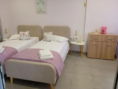 a bedroom with two beds and a table and a cabinet at Cozy apartment near to the airport in Kouvarás