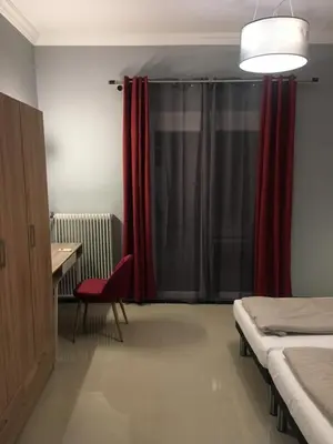 a room with two beds and a desk and a red curtain at Joges 2 in Athens