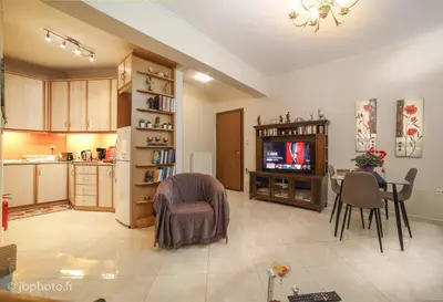 a kitchen and living room with a table and a television at Mary's House Apartment 10 min from Athens Airport in Markopoulo