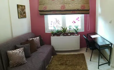 a living room with a couch and a table and a window at Mary's House Apartment 10 min from Athens Airport in Markopoulo