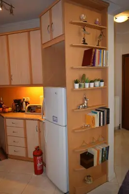 a kitchen with a refrigerator and shelves with books at Mary's House Apartment 10 min from Athens Airport in Markopoulo