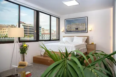 a bedroom with a white bed and large windows at Majestic City Hall in Athens
