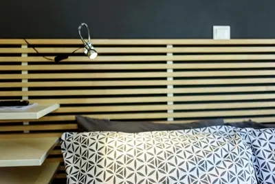 a bed with a wooden head board with a lamp at warm cozy & quiet in Athens