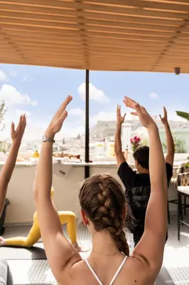 a woman with her hands in the air looking out a window at PAME House in Athens
