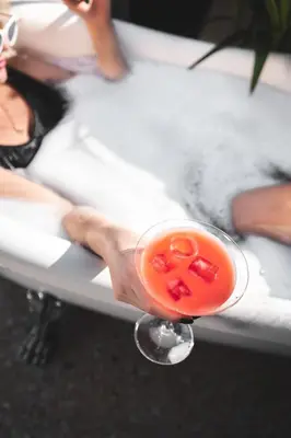 a person sitting in a bath tub with a drink at PAME House in Athens