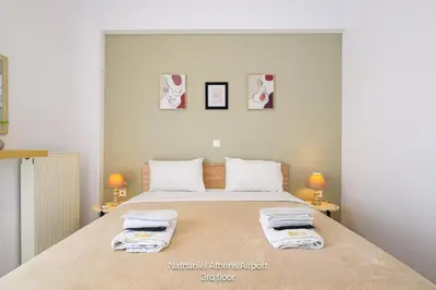 a bedroom with a large bed with towels on it at Nathaniel Athens Airport in Spáta