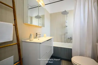 a bathroom with a sink and a toilet and a tub at Nathaniel Athens Airport in Spáta