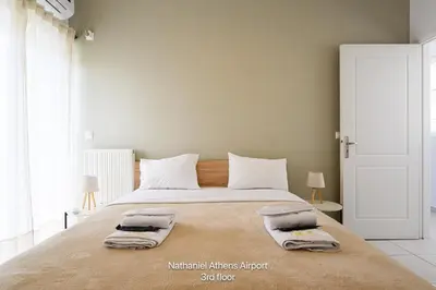 a bedroom with a large bed with two towels on it at Nathaniel Athens Airport in Spáta