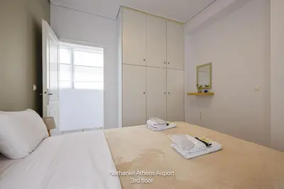 a bedroom with a large white bed with towels on it at Nathaniel Athens Airport in Spáta