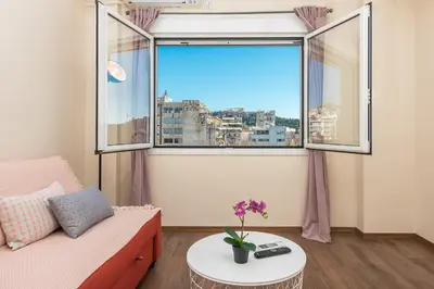 a living room with a couch and a large window at Incredible Acropolis View Flat! in Athens