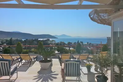 a patio with chairs and a view of the ocean at Varkiza Seaside Penthouse with Private Roof Deck in Vari