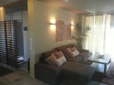 a living room with a couch and a table at Varkiza Seaside Penthouse with Private Roof Deck in Vari