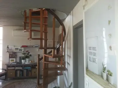 a wooden spiral staircase in a living room at Varkiza Seaside Penthouse with Private Roof Deck in Vari