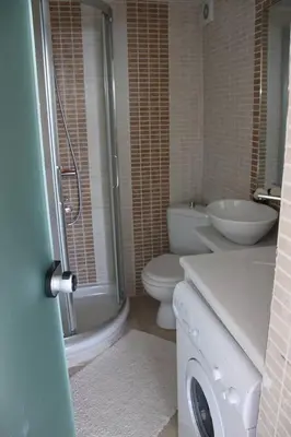 a bathroom with a toilet and a sink and a washing machine at Varkiza Seaside Penthouse with Private Roof Deck in Vari