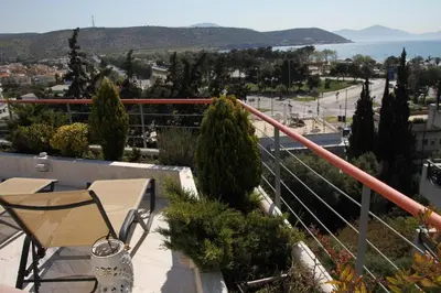 a balcony with a table and chairs and the ocean at Varkiza Seaside Penthouse with Private Roof Deck in Vari