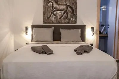 a bed with two pillows and a picture of a horse at Triple A - Acropolis View in Psiri Athens - FREE Parking! in Athens