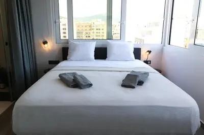 a bedroom with a large white bed with two towels on it at Triple A - Acropolis View in Psiri Athens - FREE Parking! in Athens
