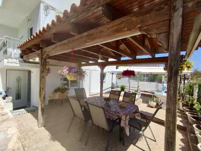 a patio with a wooden pergola and a table and chairs at Sofia's Seaview Villa Near Airport And Beach in Artemida