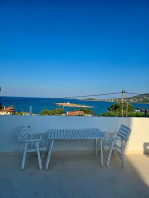 a bench and two chairs on a balcony with a view of the ocean at Sofia's Seaview Villa Near Airport And Beach in Artemida