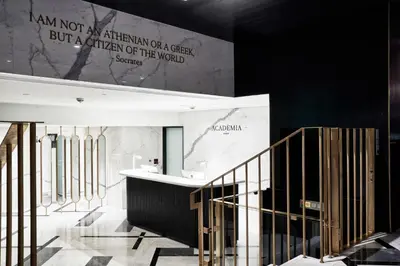 a lobby with a staircase and a sign on the wall at Academias Hotel, Autograph Collection in Athens