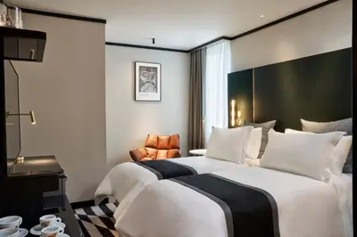 a hotel room with two beds and a chair at Academias Hotel, Autograph Collection in Athens