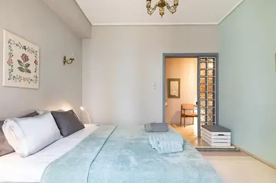 a bedroom with a large bed with a blue blanket at Olympic Mets Apartment in Athens