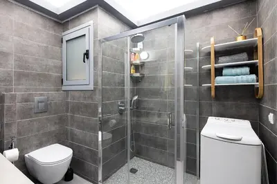 a bathroom with a toilet and a glass shower at Olympic Mets Apartment in Athens