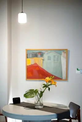 a vase of flowers on a table with a painting at Olympic Mets Apartment in Athens