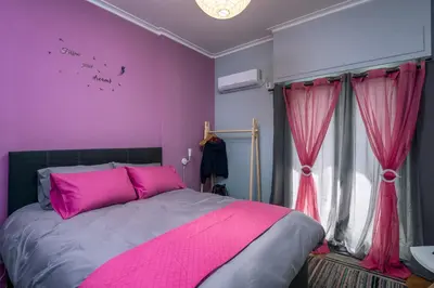 a bedroom with pink walls and a bed with pink pillows at Tonias house in Athens in Athens