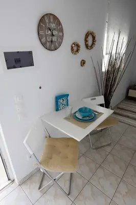 a white table and chair with a clock on the wall at INSPIRATION Guestroom with Amazing Roof Garden in Athens