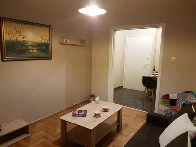 a living room with a table and a couch and a door at Katehaki Metro Flat in Athens