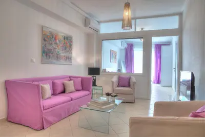 a living room with a pink couch and two chairs at Downtown Glyfada smart apartment in Athens