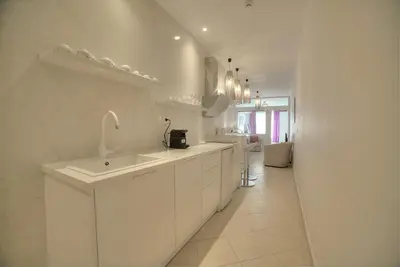 a white kitchen with a sink and a counter at Downtown Glyfada smart apartment in Athens
