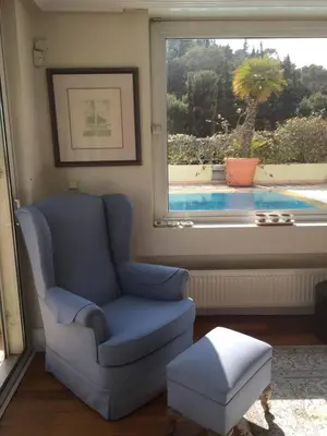 a living room with a blue chair and a window at Luxury Penthouse with Private Roof Swimming Pool in Athens