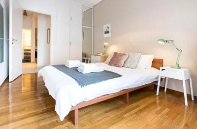 a bedroom with a large white bed with wooden floors at 1 KM from The Acropolis 1 Bedroom Apt in Athens