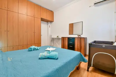 a room with a bed with blue sheets and a television at Manolitos Apartments 5 in Athens