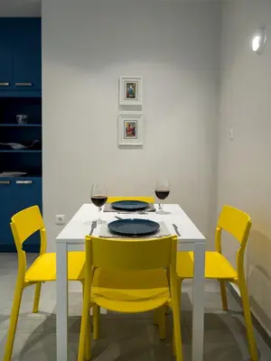 a dining room table with yellow chairs and wine glasses at Central Cozy Studio with a Secret Garden in Athens