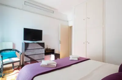 a bedroom with a bed and a tv and a chair at At Trendy Glyfada's Center in Athens
