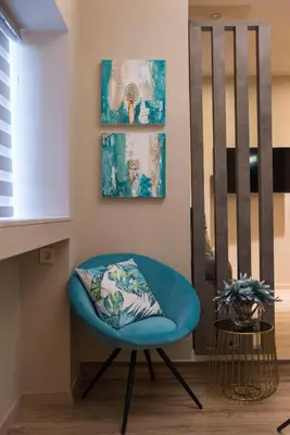 a blue chair in a living room next to a window at Wisdom Residence Luxury Apartments at Plaka in Athens