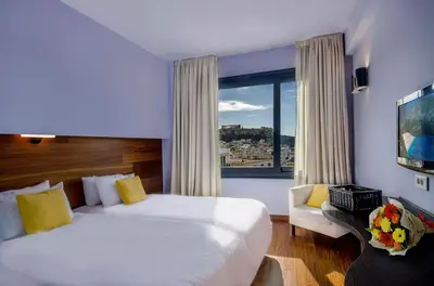 a hotel room with two beds and a window at Athens Center Square Hotel in Athens