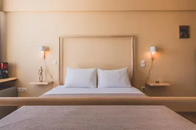 a bedroom with a bed with white sheets and two lamps at Acropolis View - Living Stone Sapphire Apartment in Athens