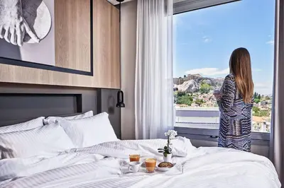 a woman standing in a bedroom looking out the window at Urban Frame Plaka in Athens