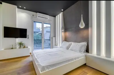 a bedroom with a large white bed and a window at Zolie Apartment in Athens