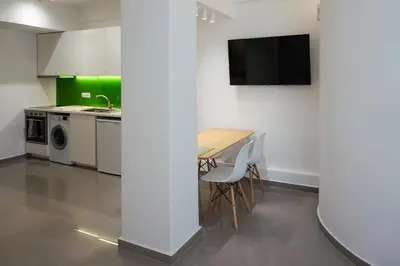a kitchen with a table and a tv on a wall at KYMA Apartments - Athens Acropolis 21 in Athens