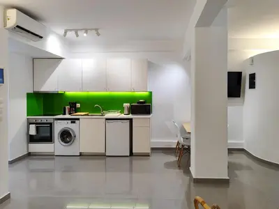 a kitchen with white cabinets and a green wall at KYMA Apartments - Athens Acropolis 21 in Athens