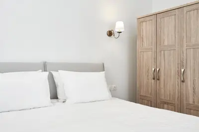 a bedroom with a white bed and a wooden cabinet at Luxury n Chic Athens Museum Apt in Athens
