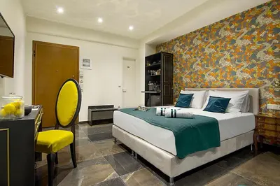 a bedroom with a large bed and a yellow chair at Athens Imperial Suites - Luxury Living in Athens