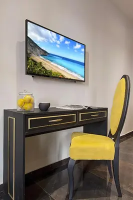 a desk with a television on a wall with a chair at Athens Imperial Suites - Luxury Living in Athens